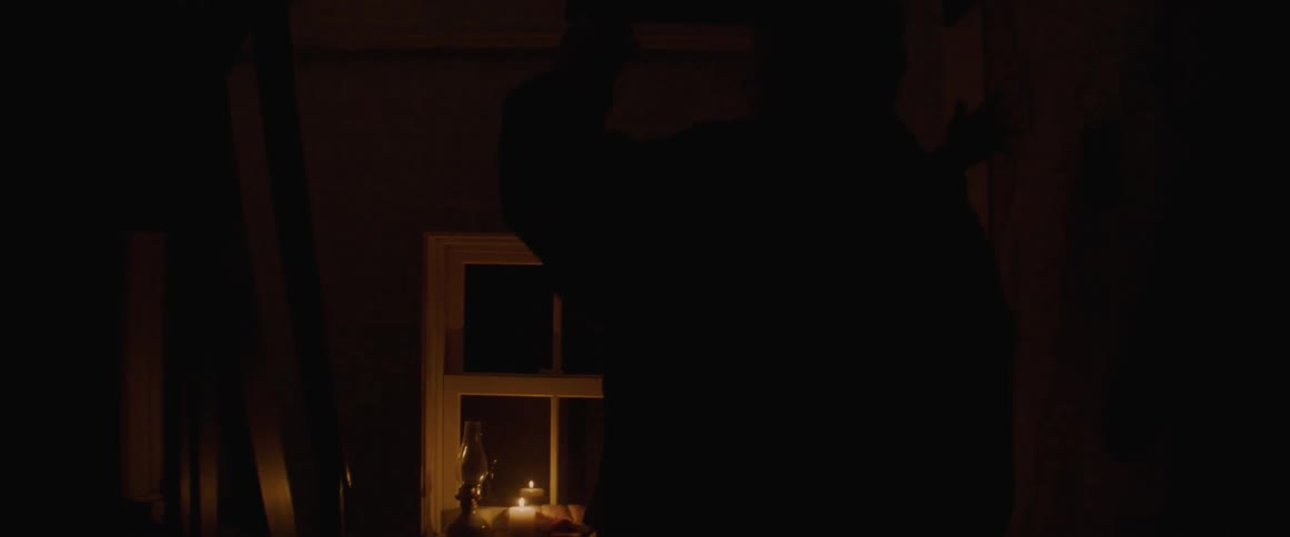 Old man and woman dancing together inside the house in front of a candle lit at the window