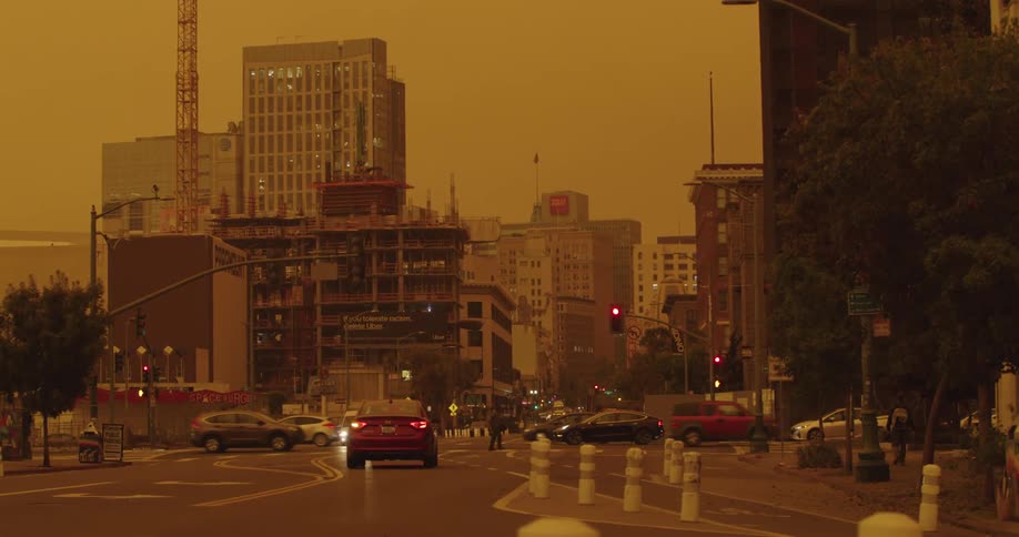 Traffic flows through intersection under amber sky