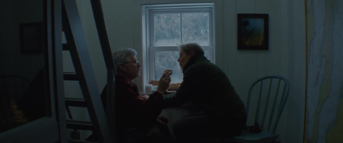 A man and woman talk and eat at home