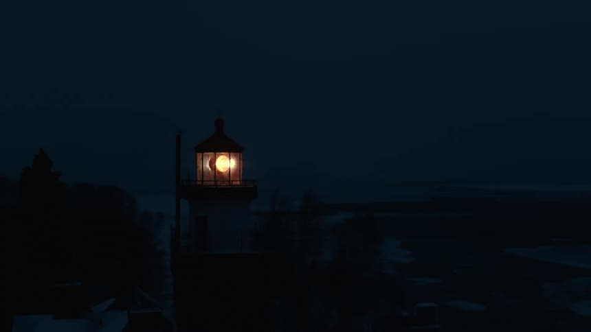 A lighthouse beacon shines brightly in the darkness
