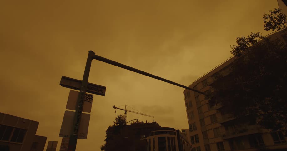 Yellow tinted footage traffic signs under the clouds moving over the skyline of a city