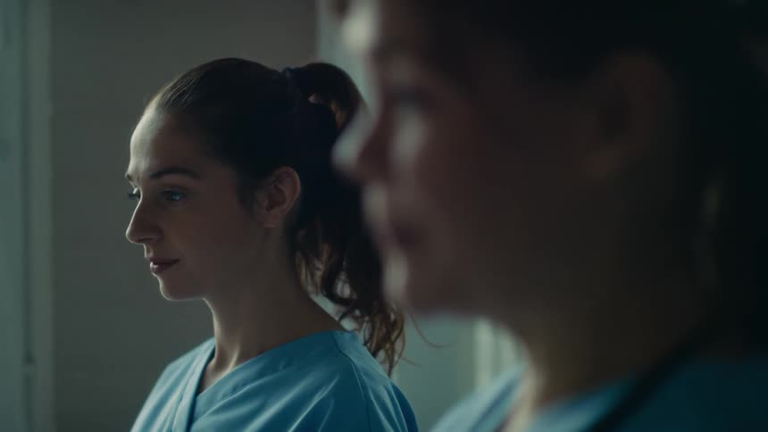 Medical personnel wearing scrubs stand nodding and talking