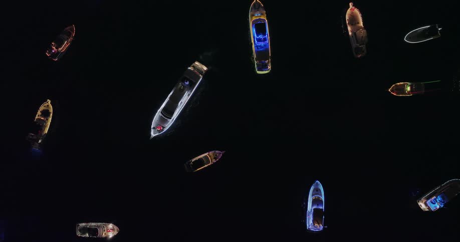 Boats covered in colorful lights float together on Lake Union at night