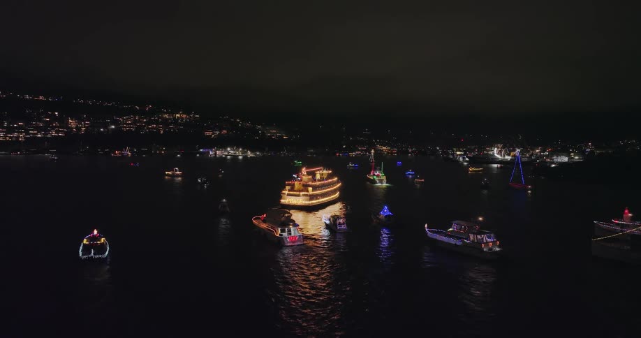 Lighted Christmas ships start to gather near the shore of Gasworks Park with Fremont and Queen Anne in the distance