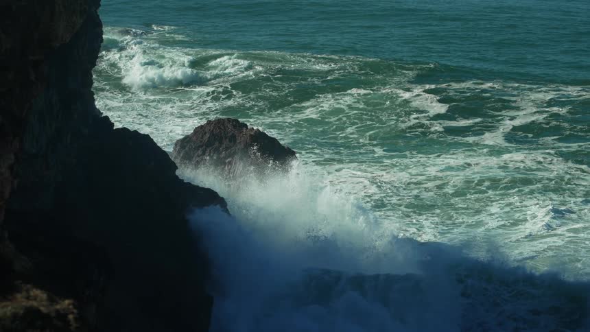 Ocean waves crashing over and around the rocks on the coast