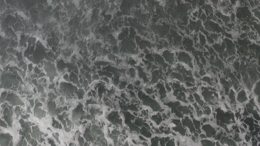 Aerial view of waves rolling in splashing and foaming