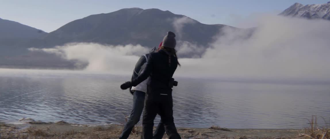 Couple Laughing and Giving High Fives Beside a Lake in a Joyful Outdoor Moment.