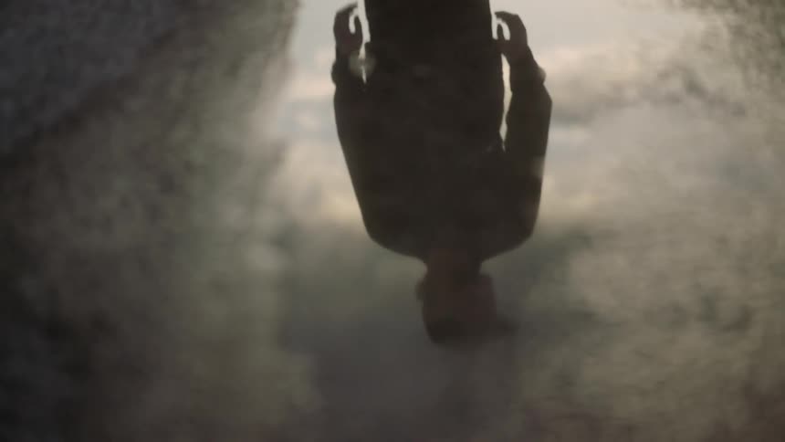 A man is reflected in a puddle as he stands outside