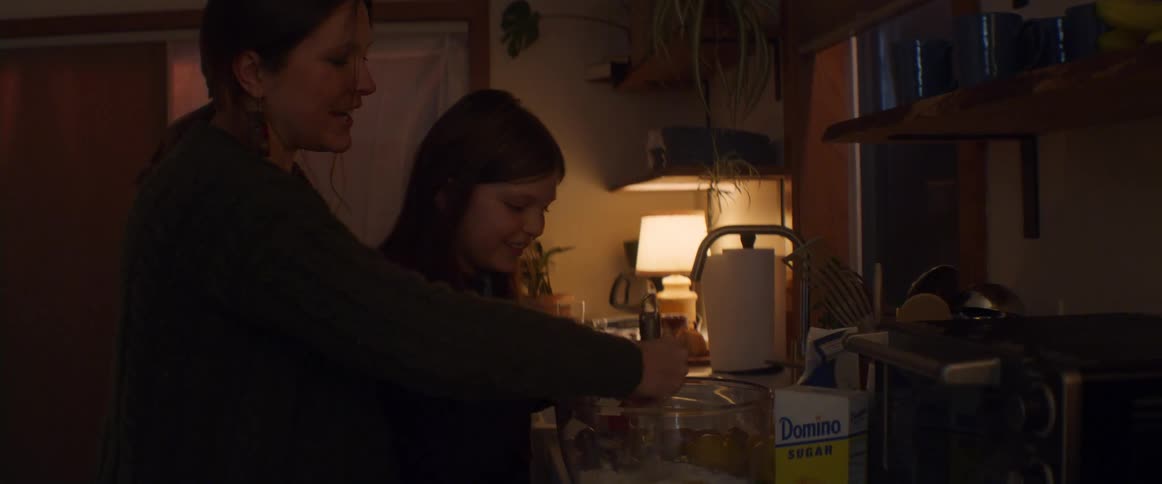 Pregnant mother and daughter cook together in kitchen