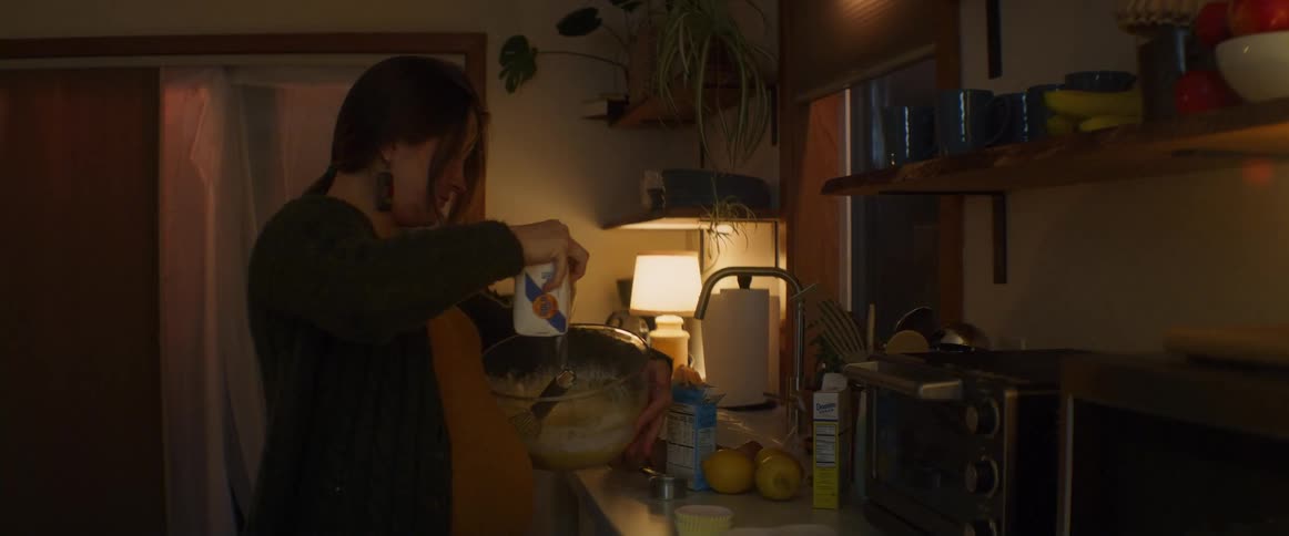 Pregnant woman with ponytail and earrings stirs bowl adding powder in the kitchen