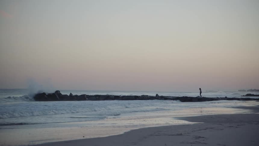 A person walks over the rocks into the water