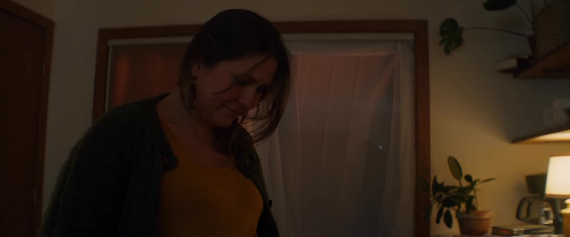 A woman stands in a room of her home touching her pregnant stomach
