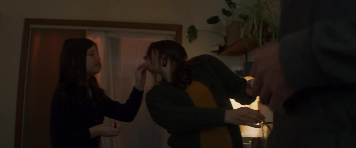 Daughter playfully gives her mother a taste of food while she cooks with her husband at home