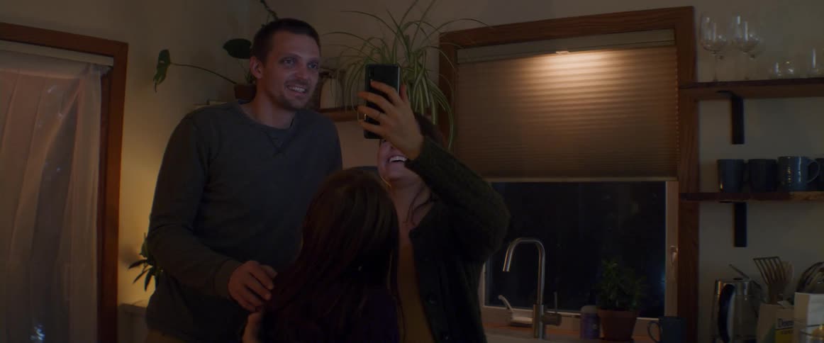 Family having a group call on a cellphone in the kitchen at home