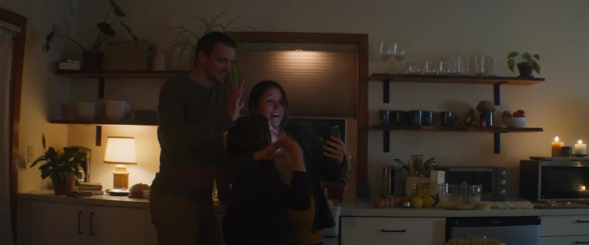 Father pregnant mother and daughter make video call on smartphone in the kitchen