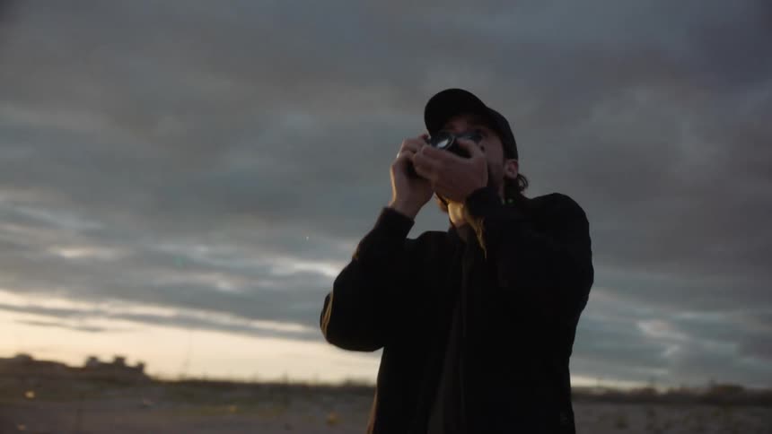 A man is outside on a very cloudy day taking photographs