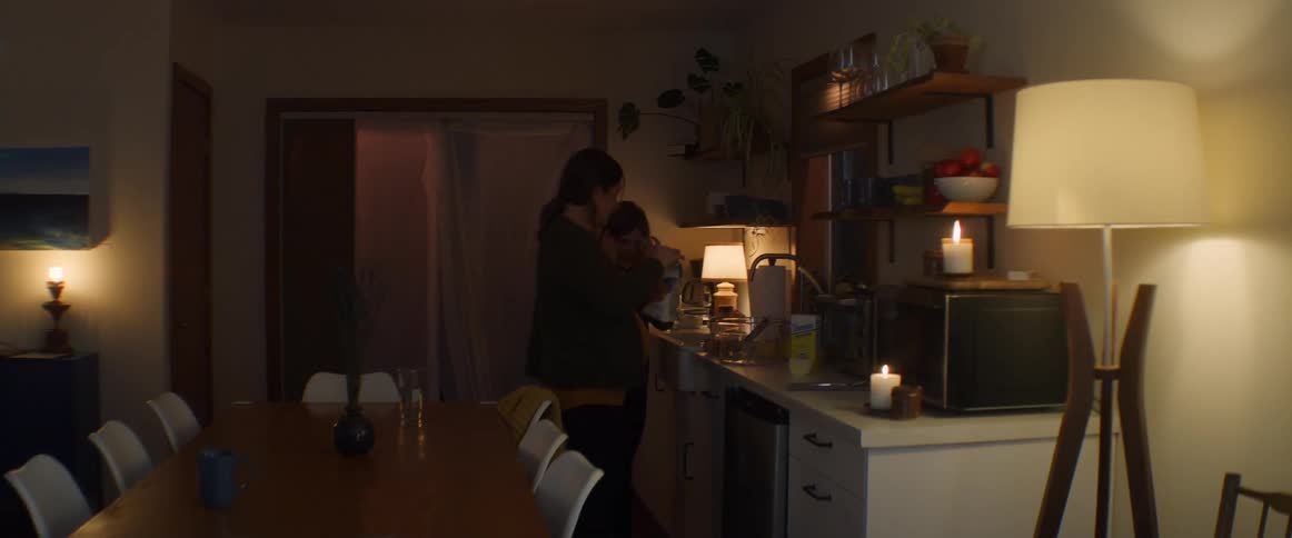 A child runs up to a woman who is cooking