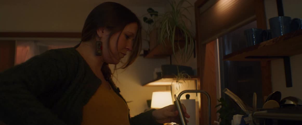 A pregnant woman stands in the kitchen stirring a large bowl