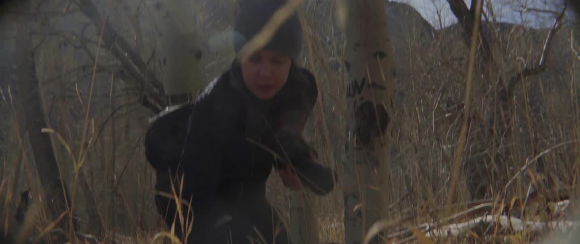 A woman holding a camera searches the ground for something