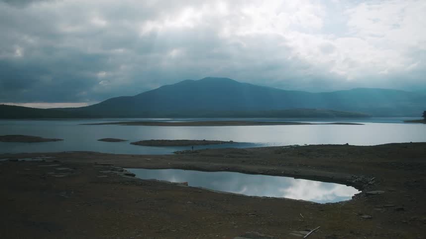 Small islands sit in a lake near a mountain range