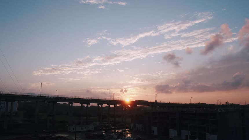 The silhouette of traffic traveling across a bridge at sunset