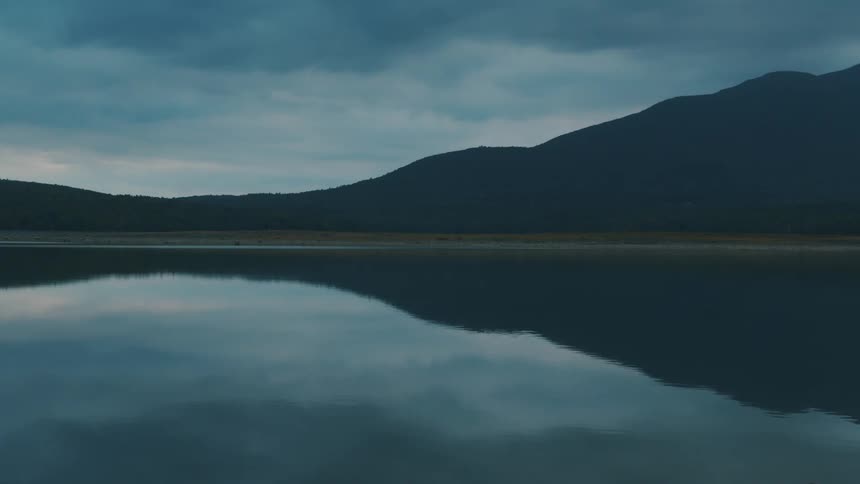 The surface water ripples gently as it reflects the hills and sky