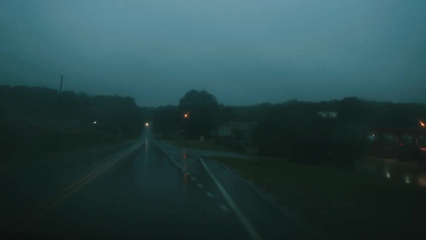 A view of a car driving down a road in the rain