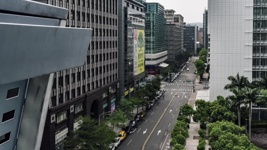 Heavy traffic passes down a busy city street lined with skyscrapers