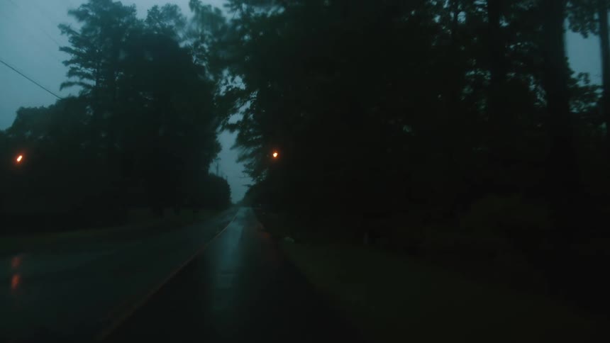 Vehicle driving on a wet rural road on a dark rainy day