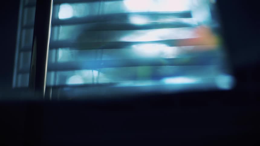 Out of focus footage of sunlight reflecting through the blinds on a window