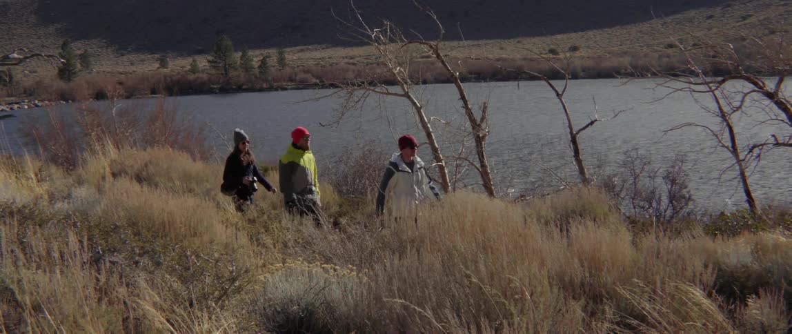 Three People Hiking by a Quiet Wilderness Pond Sharing Calm, Connected Outdoor Moments.