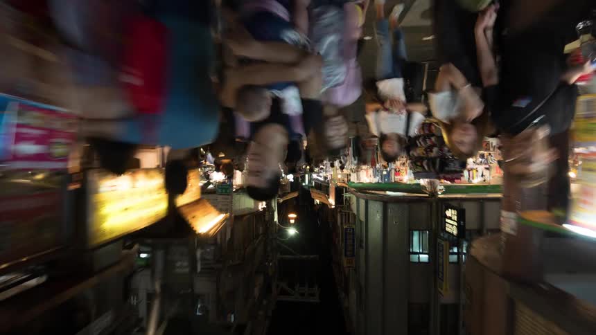 Pedestrians move along crowded street passing stores