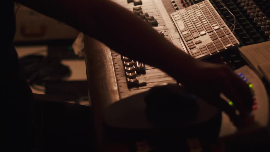 A sound mixer moves switches in the studio