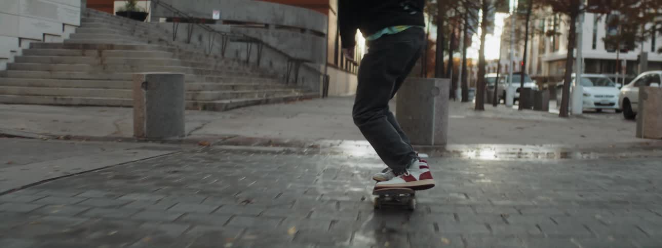 Young man rides a skateboard on the city streets at morning