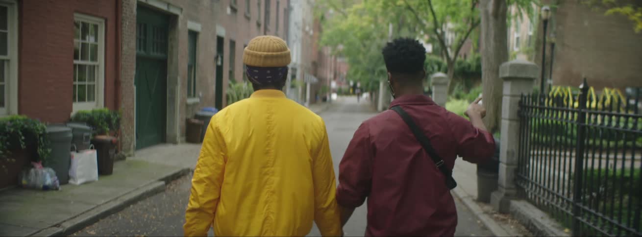 Two friends wearing colorful jackets walking on the street of a neighborhood in the city