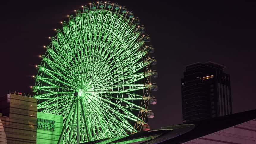 People ride a ferris wheel at night near downtown