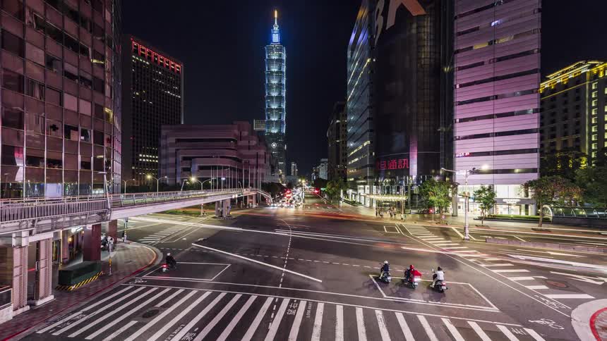 Cars are driving in a downtown city at night
