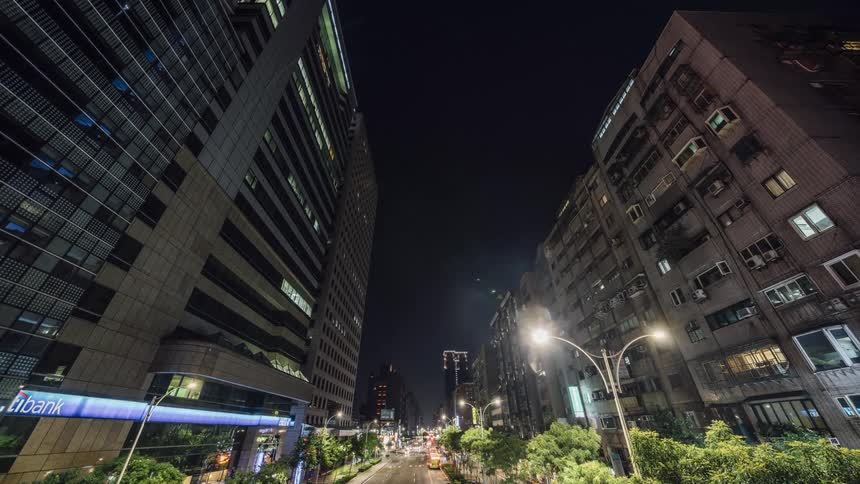 Time lapse of cars driving down a city street with apartment buildings and businesses