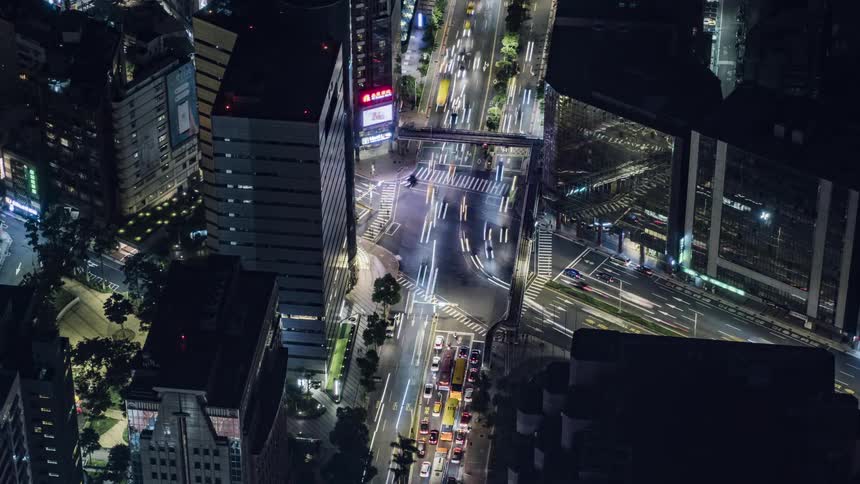 Cars traveling through a busy intersection in a city at night
