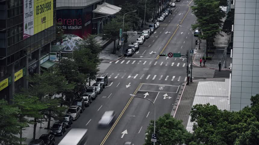 Traffic on a busy downtown intersection with many people walking on the sidewalks
