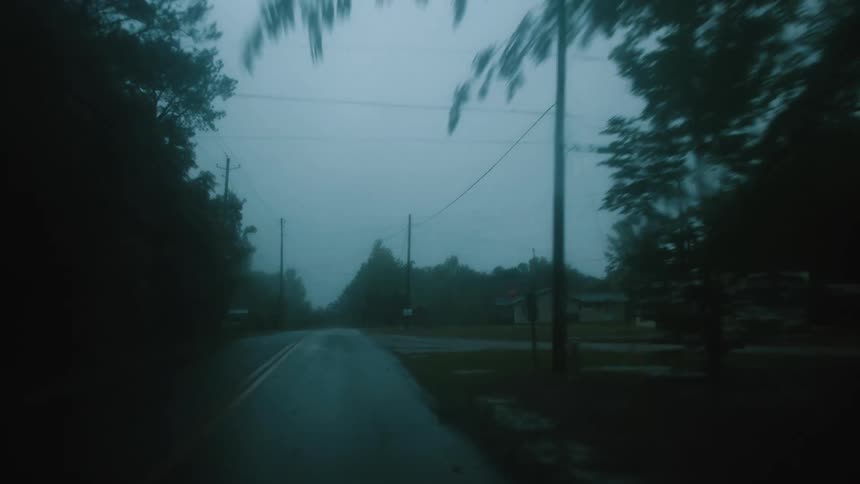 View through the windshield traveling on a neighborhood road in the rain