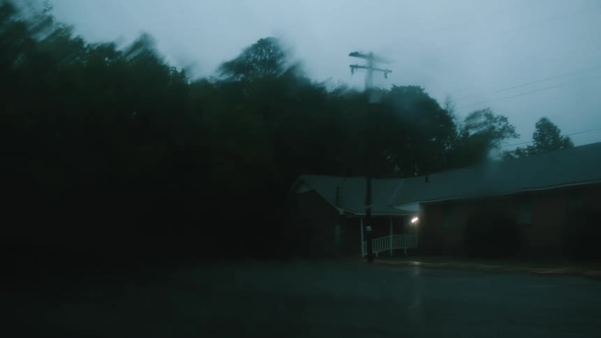 Rain falls outside a home with only the outside light turned on
