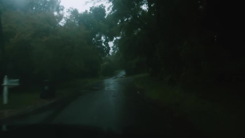 Wet road crosses through neighborhood passing and intersection and driveway