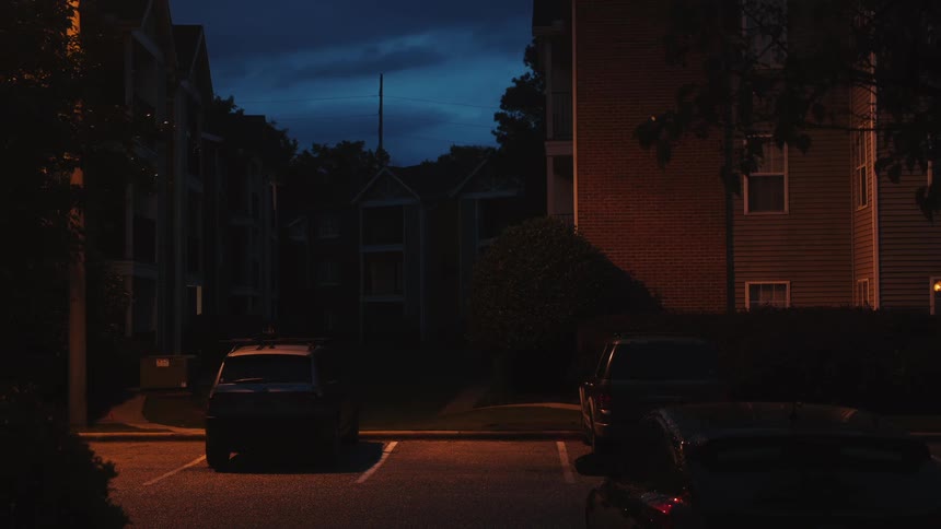 Cars are parked in a parking lot at night