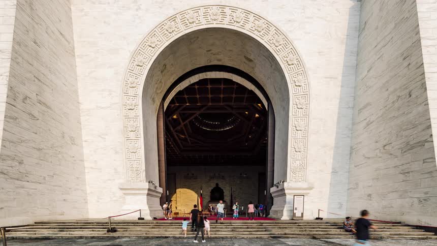 Tourists walk up the steps and enter the chiang kaishek memorial hall the watch as the large doors are closed