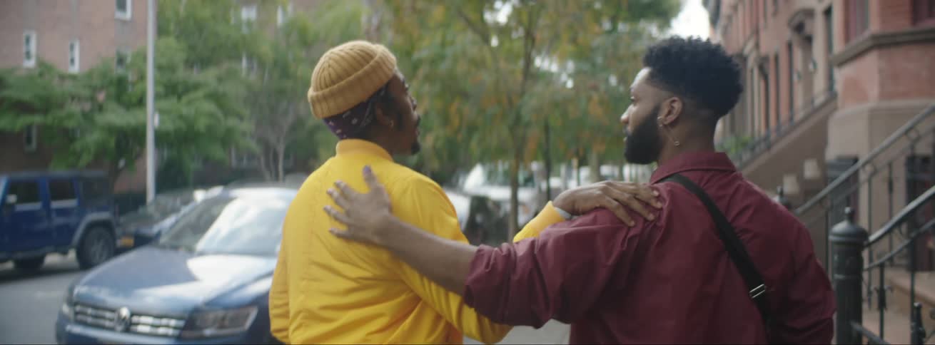 Two men walk down the street together and put their arms around one another