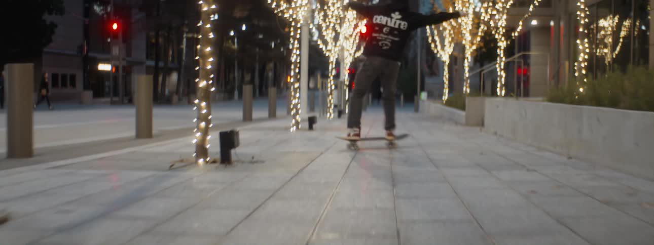 Young man rides and jumps with a skateboard on the city streets at morning
