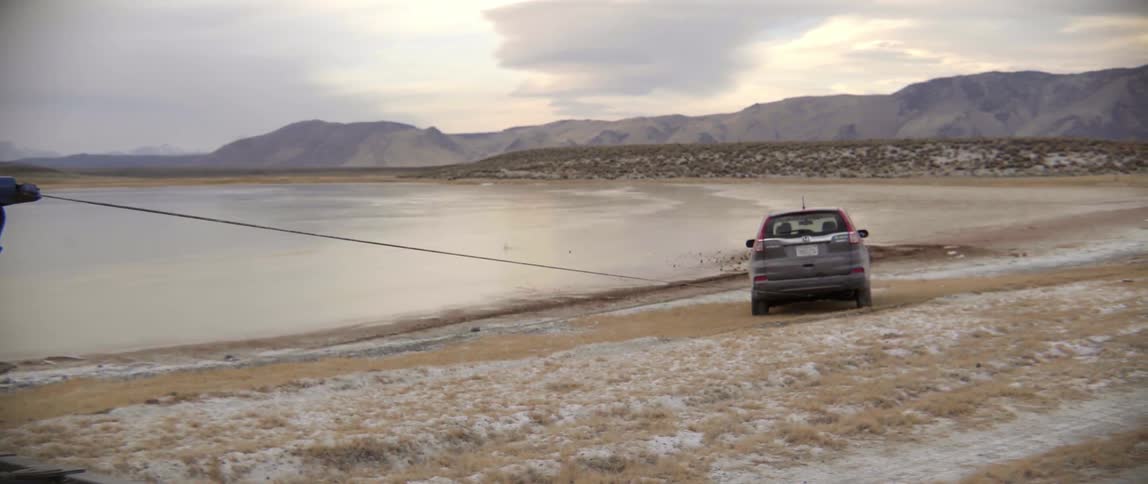 Tow Truck Driver Begins Pulling Stuck Vehicle From Water as Tension Builds on Shore.