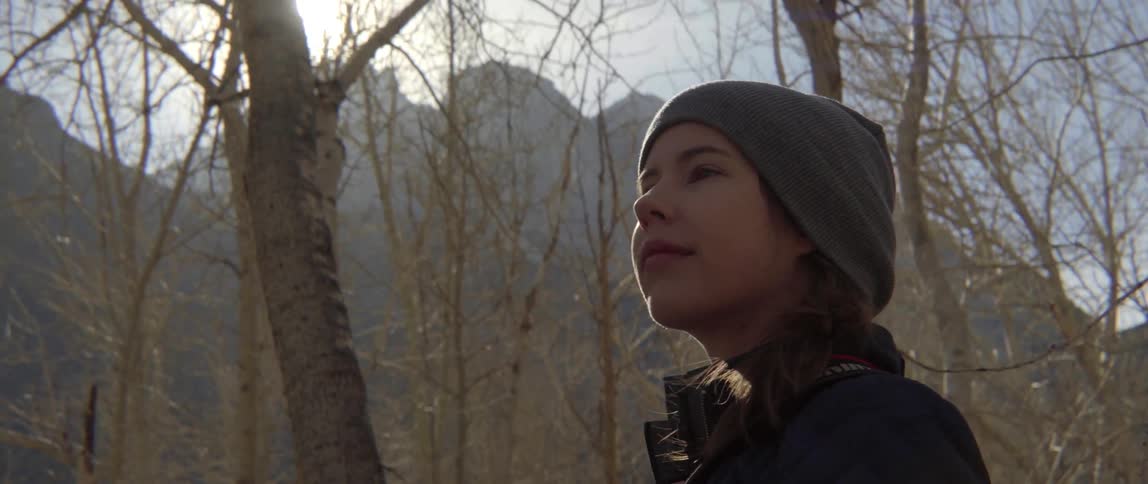 A woman is walking outside in the wilderness on a sunny day
