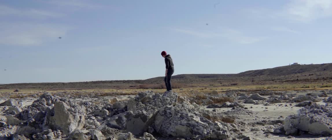 Man climbing over rocks in open field with energetic adventurous motion.